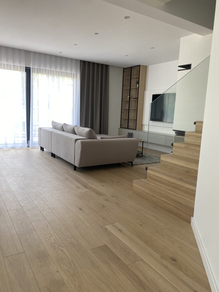 Duży jasny salon z szarą kanapą